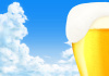 泡が溢れたビールと青空の背景 ピルスナーグラス